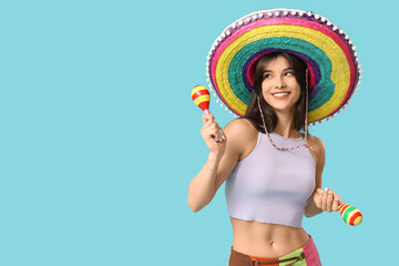 Young woman with colorful sombrero and maracas on blue background. Cinco de Mayo celebration