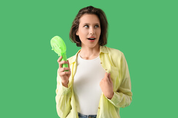 Young woman with portable electric fan on green background