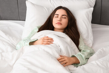 Pretty young woman sleeping in cozy bed