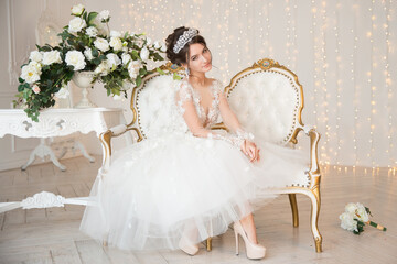 Bride. Wedding. The bride in a short dress with lace in the crown earrings. Wedding bouquet, makeup, hairstyle. Wedding Style