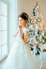 Fototapeta premium Bride. Wedding. The bride in a short dress with lace in the crown earrings. Wedding bouquet, makeup, hairstyle. Wedding Style