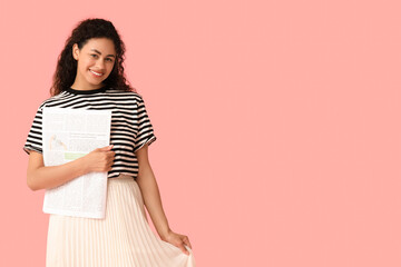 Beautiful young African-American woman with newspaper on pink background