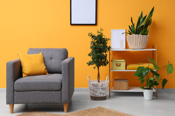 Interior of living room with cozy armchair, picture frame, houseplant and shelving unit