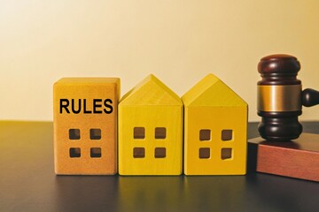 Wooden blocks representing houses and a "RULES" block beside a judge's gavel, symbolizing housing regulations, legal compliance, and real estate law.