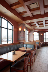 Fototapeta premium Comfortable restaurant interior with wooden furniture, tables and chairs, brick walls, warm light from wall lamps, large windows revealing winter landscape, coffered ceiling design