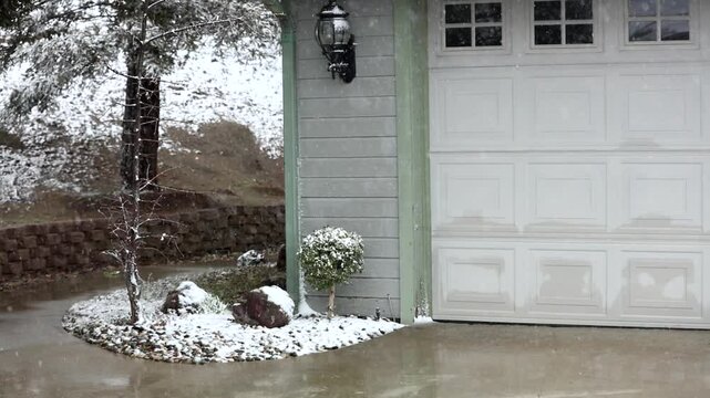 A light dusting of snow falling on a walkway to a house. 