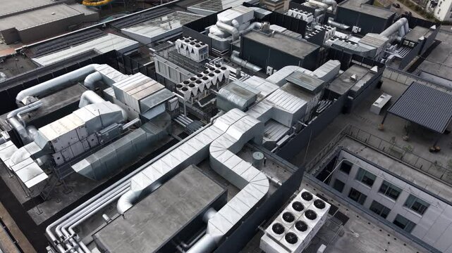 Overhead view of a commercial building rooftop with extensive HVAC ductwork, ventilation systems, and cooling units in an organized layout.