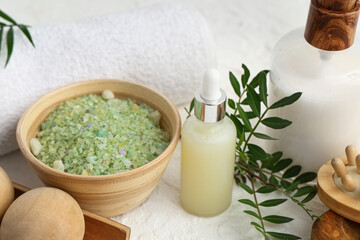 Plakat Bowl of sea salt, cosmetic products, spa accessories and plant branch on light table, closeup
