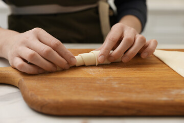 Woman making croissant at light table indoors, closeup