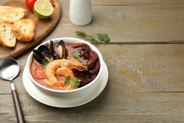 Delicious seafood soup served on wooden table. Space for text
