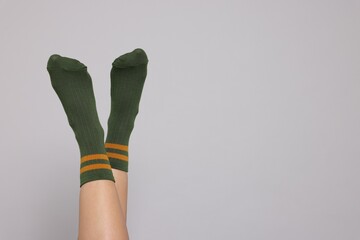 Woman in stylish socks on light grey background, closeup. Space for text