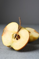 Halves of overripe apple on grey wooden table, closeup