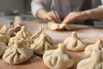 Fototapete Rund Woman making khinkali on table in kitchen, closeup © New Africa