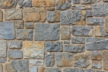 Textured stone wall with varied grey and beige bricks