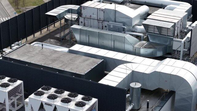 Overhead view of a commercial building rooftop with extensive HVAC ductwork, ventilation systems, and cooling units in an organized layout.