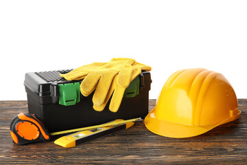 Hardhat, toolbox and construction tools on wooden table against white background