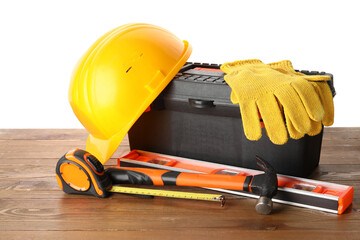 Hardhat, toolbox and construction tools on wooden table against white background