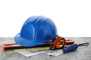 Hardhat, house plan and construction tools on grunge table against white background