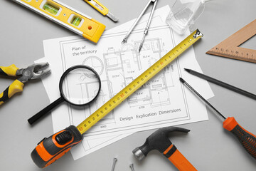 Construction tools, magnifying glass and house plan on grey background