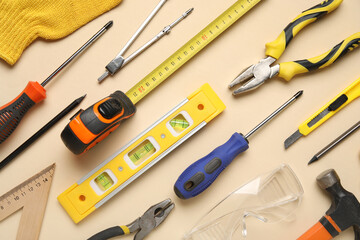 Arrangement of different construction tools on beige background