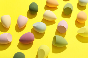 Colorful makeup sponges on yellow background