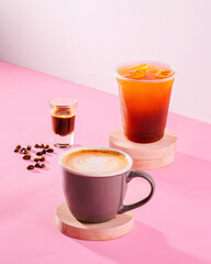 A coffee cup with a shot of espresso and a cup of tea with ice cubes. The coffee is a dark roast...