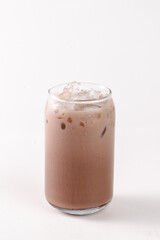 A glass of chocolate milk is sitting on a white background. The glass is half full and the milk is cold