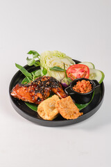 A plate of food with a piece of chicken, a piece of fried dough, and a tomato. The chicken is cooked and has a brown glaze on it. The fried dough is crispy and golden brown. The tomato is sliced