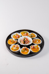 A plate of food with a black rim and a white background. The food is a variety of small, yellowish-orange shells