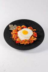 A plate of food with a fried egg and rice. The plate is black and white. The food looks delicious and appetizing