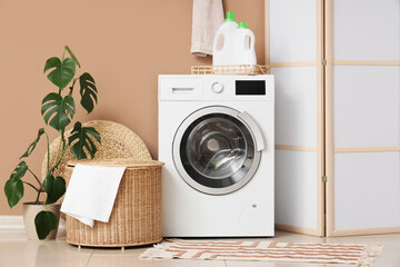Interior of laundry room with modern washing machine near brown wall