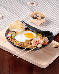 A plate of food with a fried egg and vegetables on top of a wooden board. The plate is on a table with a floral patterned cloth
