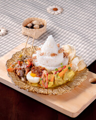 A plate of food with a lot of different ingredients on it. The plate is on a wooden board