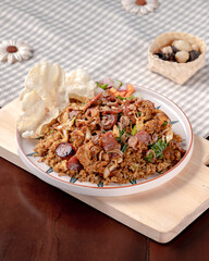 A plate of food with a piece of fried rice on top. The plate is on a wooden table