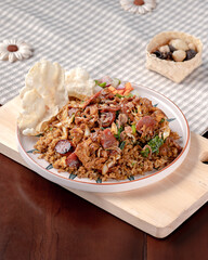 A plate of food with a piece of fried rice on top. The plate is on a wooden table