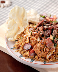 A plate of food with a piece of fried rice on top. The rice is covered in sauce and has meat on top. The plate is on a wooden table