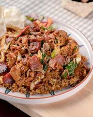 A plate of food with meat and rice on it. The plate is on a wooden table. The food looks delicious and appetizing