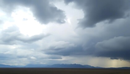 Obraz premium Dramatic rain clouds over a remote landscape with distant mountain range