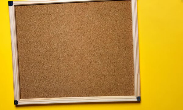 Wooden-framed corkboard on bright yellow background