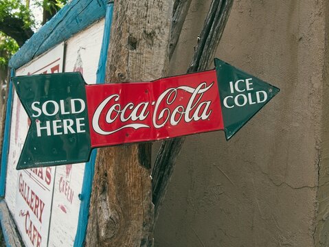Green and red Coca-Cola vintage sign designed as a pointing arrow saying: "ice cold Coca-Cola sold here.
"