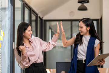 Obraz premium Two women are high fiving each other in a business setting