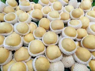 Lots of ripe pears are placed in foam net in a pile as a background texture
