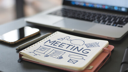 Meeting notes on a desk with a laptop and smartphone ready for collaboration and planning.