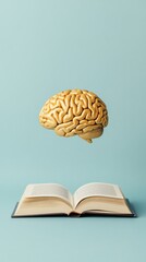 A golden brain floating above an open book, symbolizing creativity and knowledge. Future skills and continuous learning. Growth mindset.