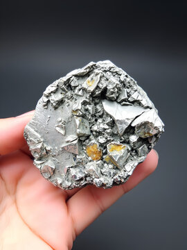 Rough silver ilmenite fragment showcasing metallic and oxidized surfaces in hand