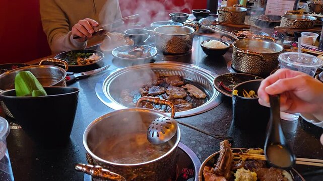 Asian Hotpot and Grill Table where people are cooking meat in the grill