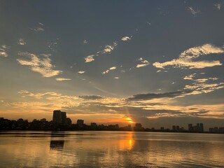 Golden Hour Reflections: Tranquil Waterfront Cityscape at Sunset with Perfect Mirror Effect on West Lake in Hanoi, Vietnam