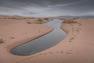 Big dune and the sand texture with the river cutting through at the foreground, Inner Mongolia, China. Background, copy space for text, beige colors, panorama