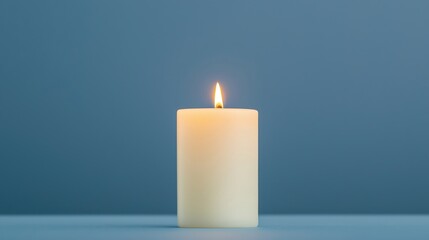 A white candle with a gentle flame stands against a soft blue background, creating a serene and calming atmosphere.
