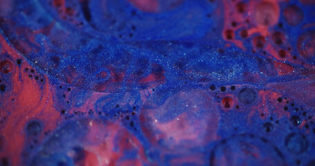 Glitter ink. Defocused fluid flow. Beautiful blue red color liquid paint transparent bubbles motion...